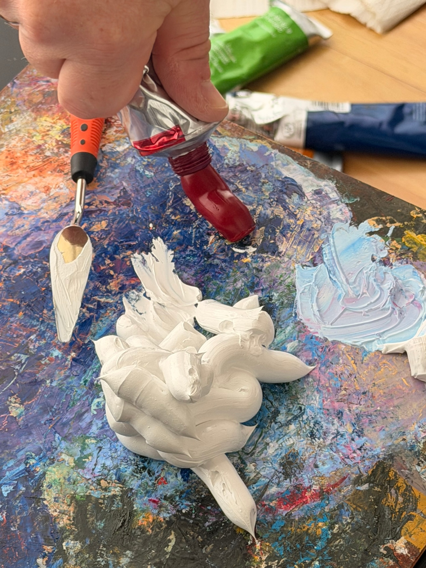 Red oil paint and a palette knife on Evgeny Maximov's mixing palette