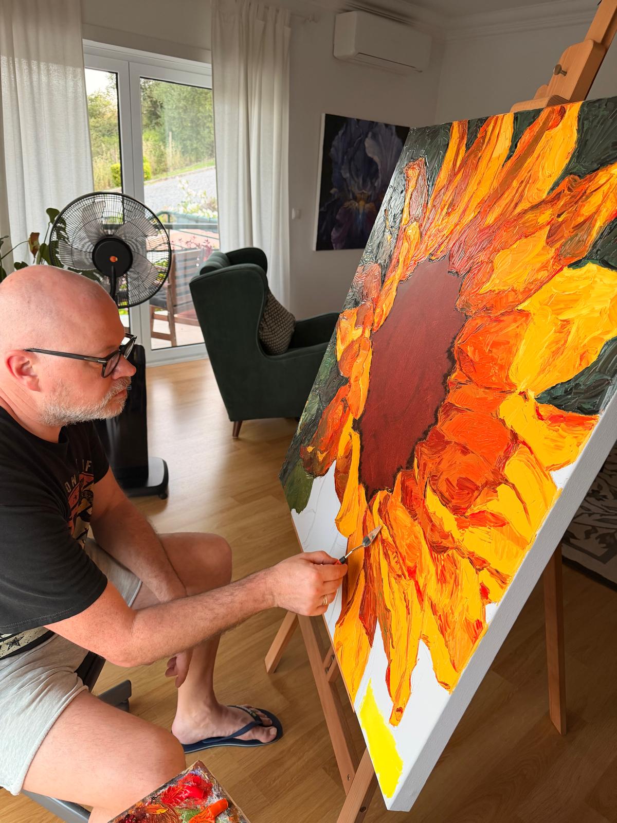 Evgeny Maximov painting the Sunflower on the easel in his studio